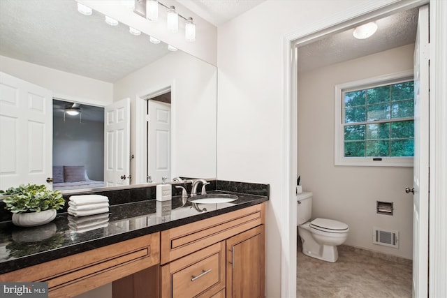 bathroom with toilet, vanity, a textured ceiling, and baseboards