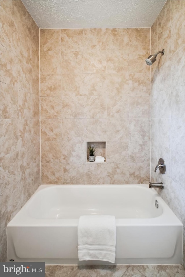 full bathroom with shower / tub combination, a textured ceiling, and tile walls