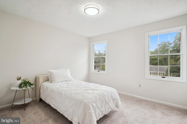 carpeted bedroom featuring multiple windows and baseboards