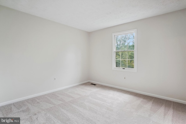 spare room with light carpet and baseboards