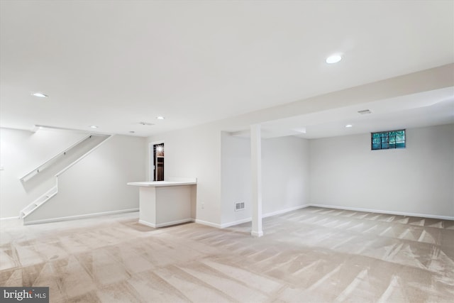 finished below grade area featuring light carpet, recessed lighting, stairs, and baseboards