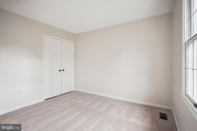 unfurnished bedroom featuring carpet, baseboards, and a closet