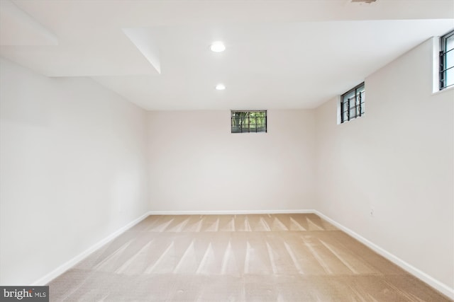 below grade area with baseboards, light colored carpet, and recessed lighting