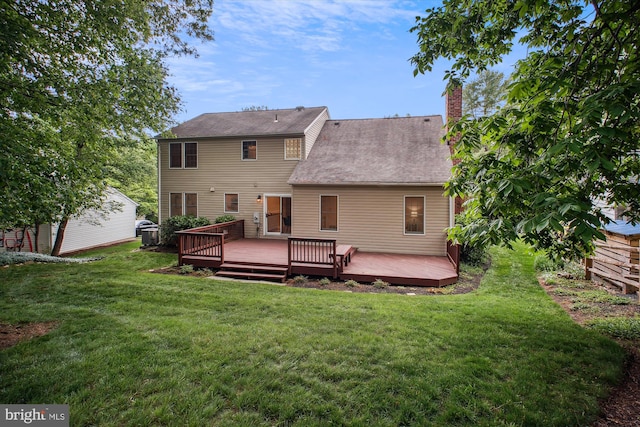 rear view of property featuring a lawn, a deck, a chimney, and roof with shingles