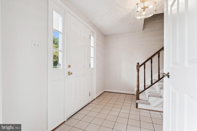foyer entrance with stairway, light tile patterned floors, and baseboards