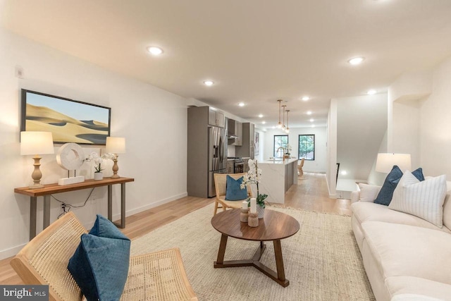 living area with light wood-style floors, baseboards, and recessed lighting