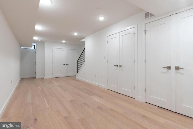 finished basement with light wood-style flooring, recessed lighting, baseboards, visible vents, and stairs
