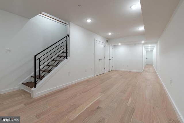 basement with light wood finished floors, stairs, baseboards, and recessed lighting