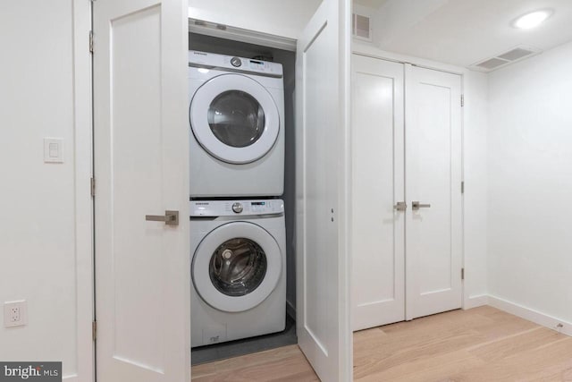 washroom with light wood-type flooring, visible vents, laundry area, and stacked washer / drying machine