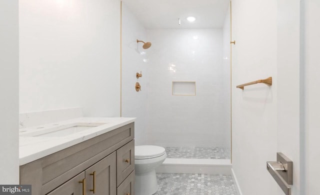 full bathroom featuring vanity, toilet, tile patterned flooring, and tiled shower