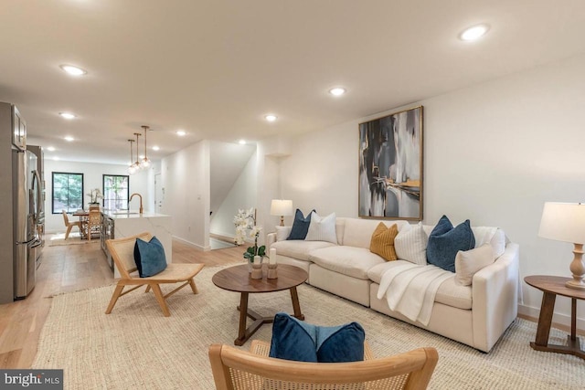 living area with light wood-style flooring, baseboards, and recessed lighting