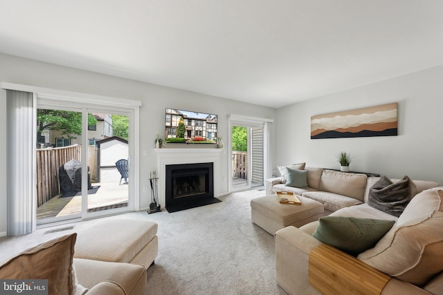 living room featuring carpet, plenty of natural light, and a fireplace with flush hearth