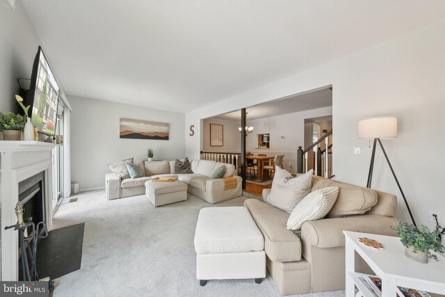 living room featuring carpet flooring, a chandelier, a fireplace, and stairway