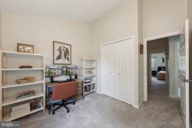 carpeted home office with baseboards and a towering ceiling