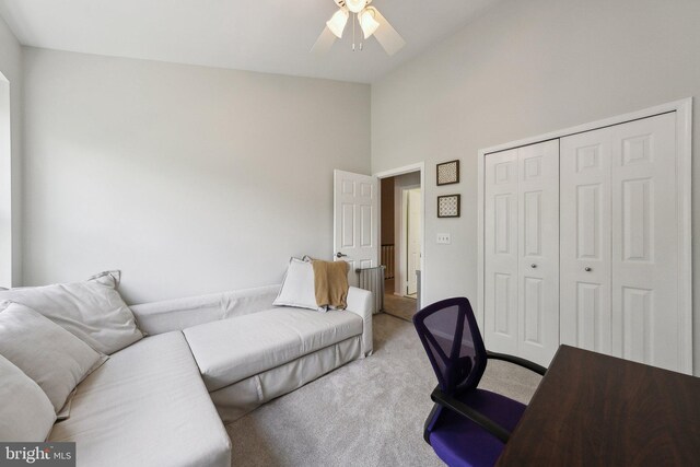 carpeted office space featuring a ceiling fan and high vaulted ceiling