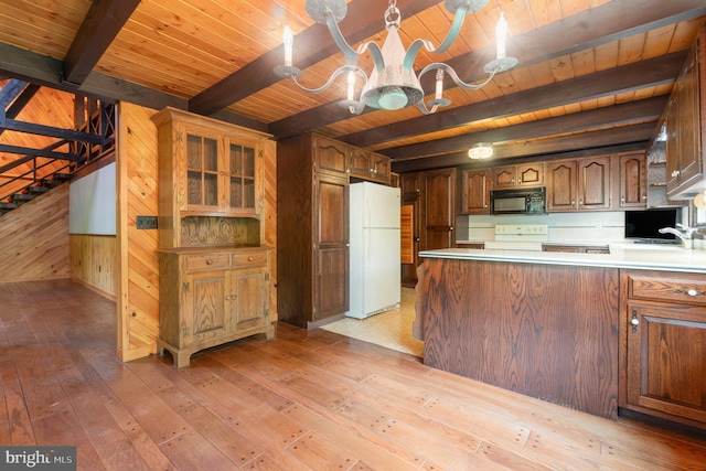 kitchen with freestanding refrigerator, wood ceiling, black microwave, wooden walls, and a chandelier