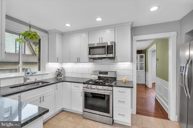 628 Mason Ave, Drexel Hill, PA 19026 - kitchen featuring stainless steel appliances, a sink, dark stone counters, white cabinetry, and wainscoting