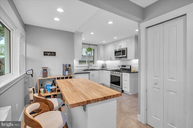 628 Mason Ave, Drexel Hill, PA 19026 - kitchen with appliances with stainless steel finishes, a sink, wood counters, decorative backsplash, and white cabinetry