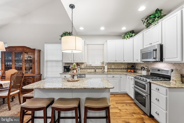 606 Garden Gate Dr, Middletown, DE 19709 - kitchen featuring appliances with stainless steel finishes, a sink, a kitchen bar, white cabinetry, and decorative backsplash