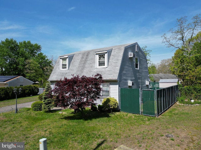 view of home's exterior featuring fence, a gambrel roof, and a lawn