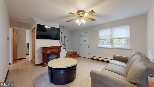 living room featuring a baseboard heating unit, stairway, light tile patterned floors, and a ceiling fan