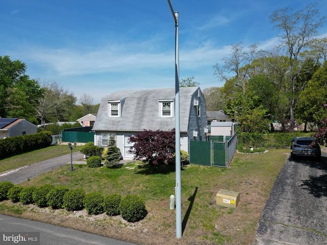 view of front of property featuring aphalt driveway, fence, a gambrel roof, and a front lawn