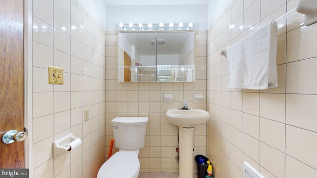 bathroom with toilet, tile walls, and a sink