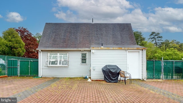 back of house with a patio area, roof with shingles, fence, and a gate