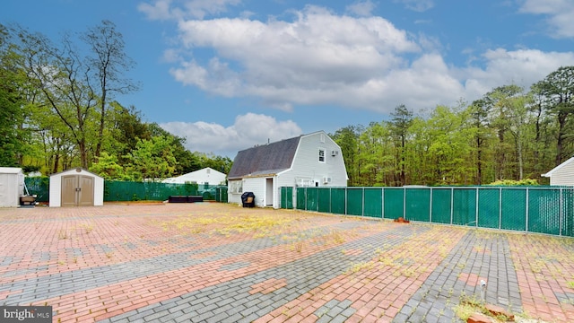 view of patio with a storage unit, fence, and an outbuilding