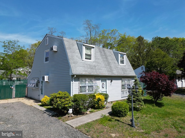 dutch colonial featuring a gambrel roof, a wall mounted air conditioner, and fence