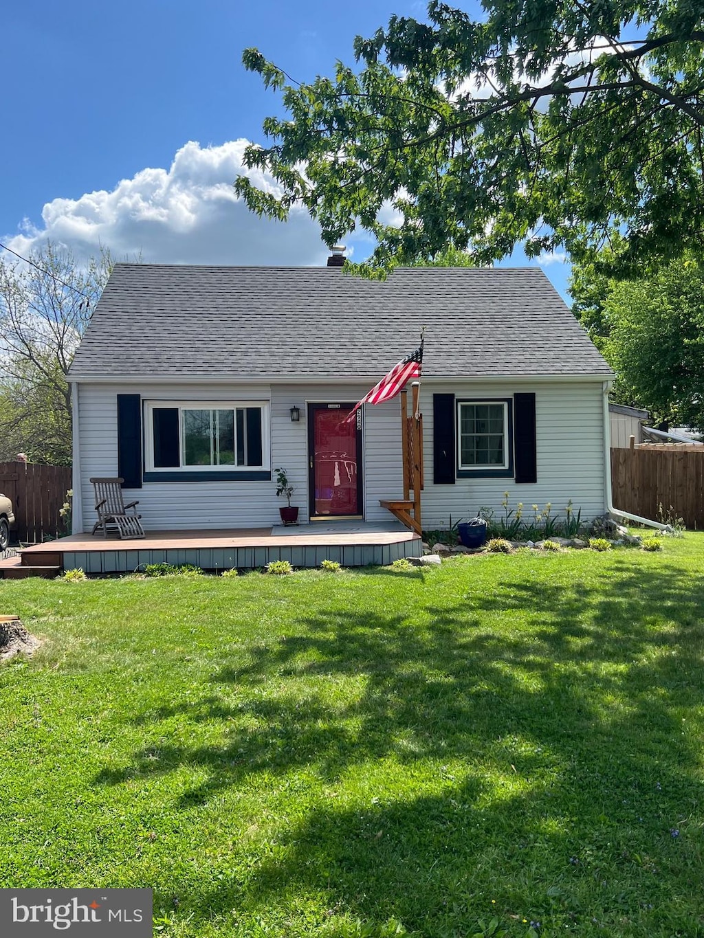 single story home with fence, a shingled roof, a front lawn, and a deck