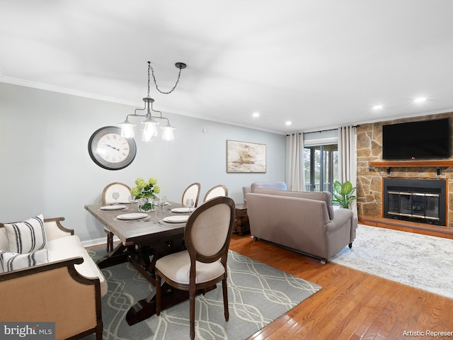 dining space with crown molding, wood finished floors, a fireplace, recessed lighting, and a chandelier