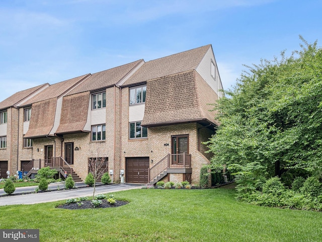 view of front of property featuring driveway, a shingled roof, a garage, a front lawn, and brick siding