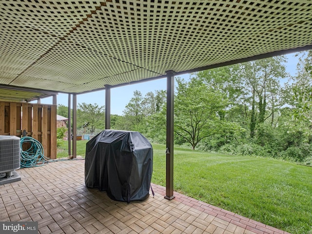 view of patio with area for grilling, central AC unit, and view of scattered trees