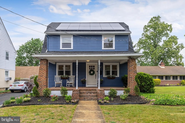 view of front of house featuring a porch, solar panels, a shingled roof, and a front lawn