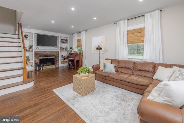 living room featuring wood finished floors, stairs, recessed lighting, and a fireplace