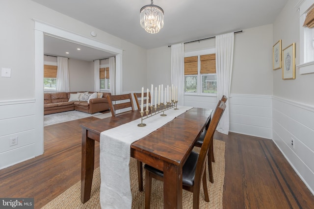dining space with wood finished floors, a chandelier, and wainscoting