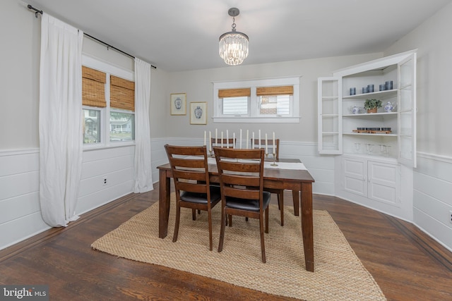 dining area featuring a chandelier, a wainscoted wall, and wood finished floors