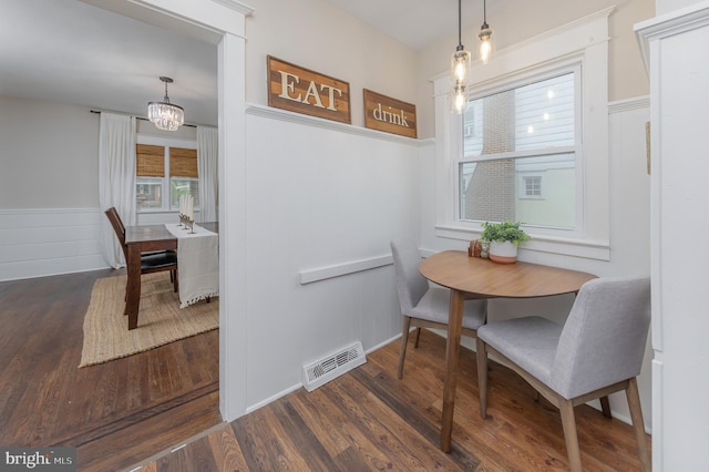 dining space with wainscoting, wood finished floors, and a chandelier