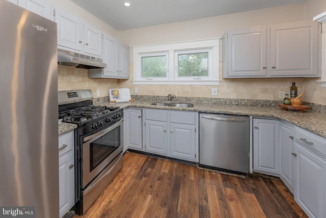 kitchen with appliances with stainless steel finishes, under cabinet range hood, a sink, backsplash, and recessed lighting