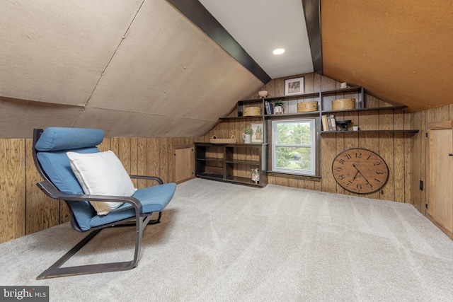 sitting room featuring wooden walls, lofted ceiling, and carpet flooring