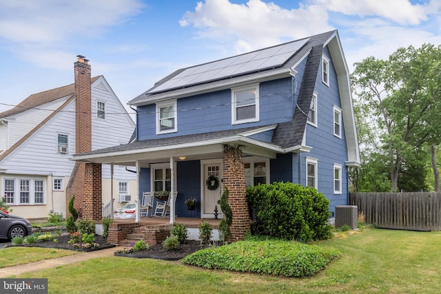 view of front of home with a porch, solar panels, roof with shingles, and central AC