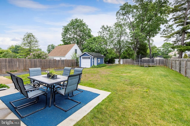 view of yard with a trampoline, outdoor dining area, a patio, and an outdoor structure
