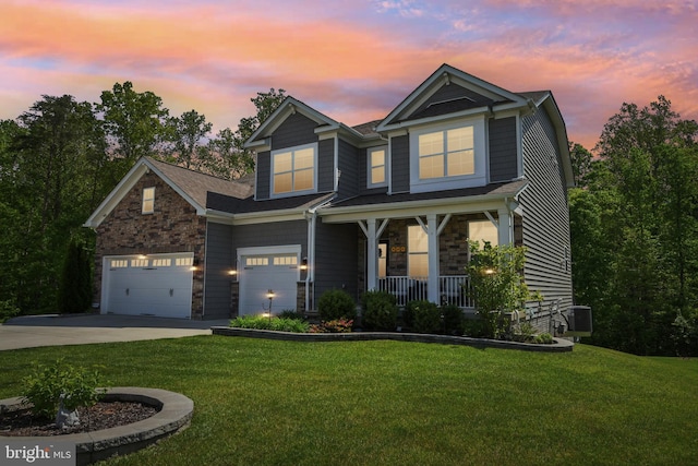 view of front facade with stone siding, concrete driveway, a porch, and a yard