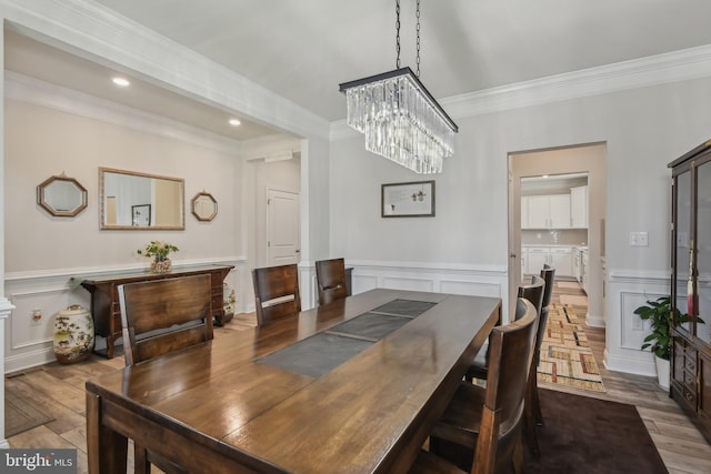 dining area with ornamental molding, a decorative wall, and wood finished floors