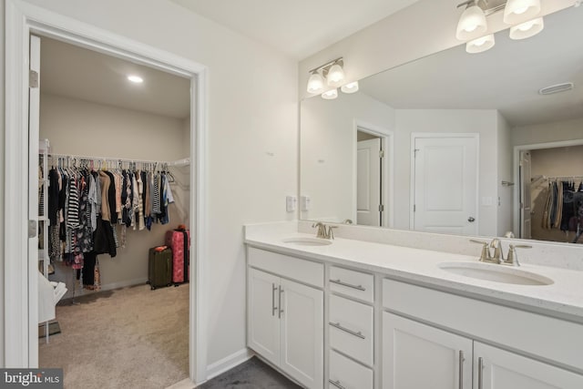 full bath featuring a sink, double vanity, a spacious closet, and visible vents