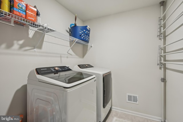 laundry room with laundry area, visible vents, washer and dryer, light tile patterned floors, and baseboards