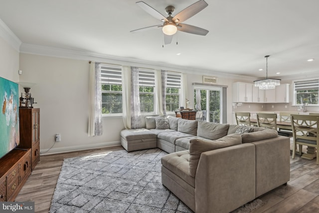 living room featuring ornamental molding, plenty of natural light, and ceiling fan with notable chandelier