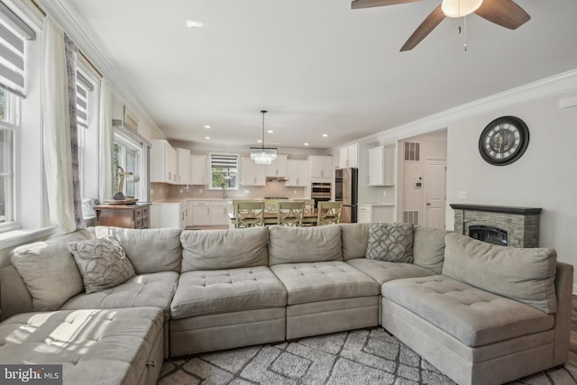 living room with ornamental molding, visible vents, recessed lighting, a fireplace, and a ceiling fan