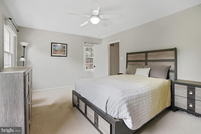bedroom featuring light colored carpet, baseboards, and a ceiling fan